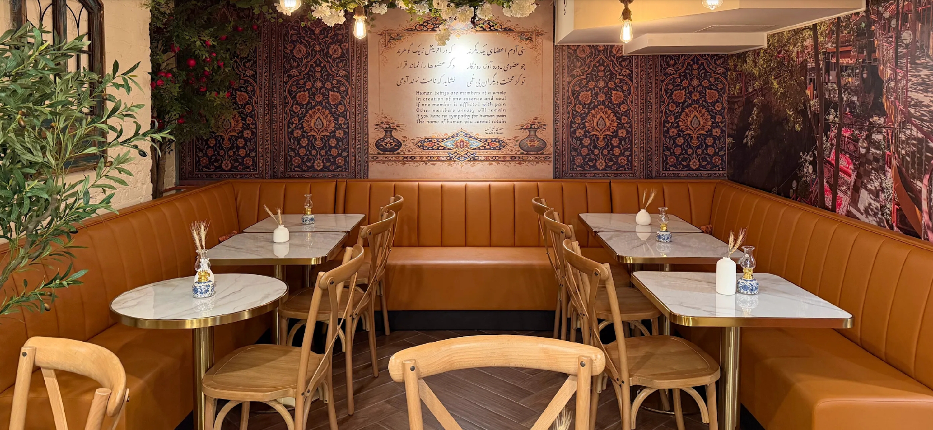 Inside Taftoon NYC — a Persian dining room with firoozeh turquoise tiled columns, emerald velvet banquettes, and a table set with saffron tahdig and fresh taftoon bread
