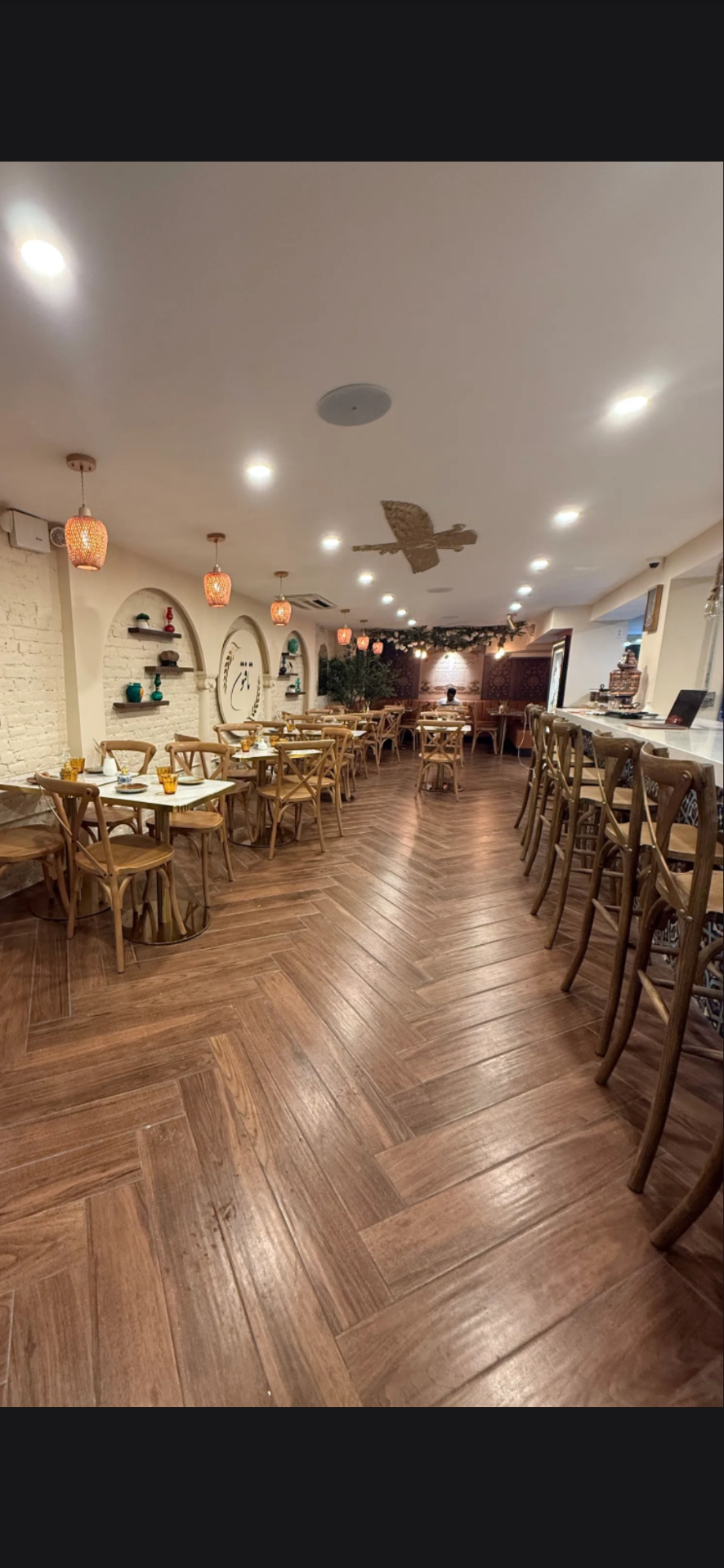 Herringbone floor, rattan pendant lanterns, and Persian arches at Taftoon NYC