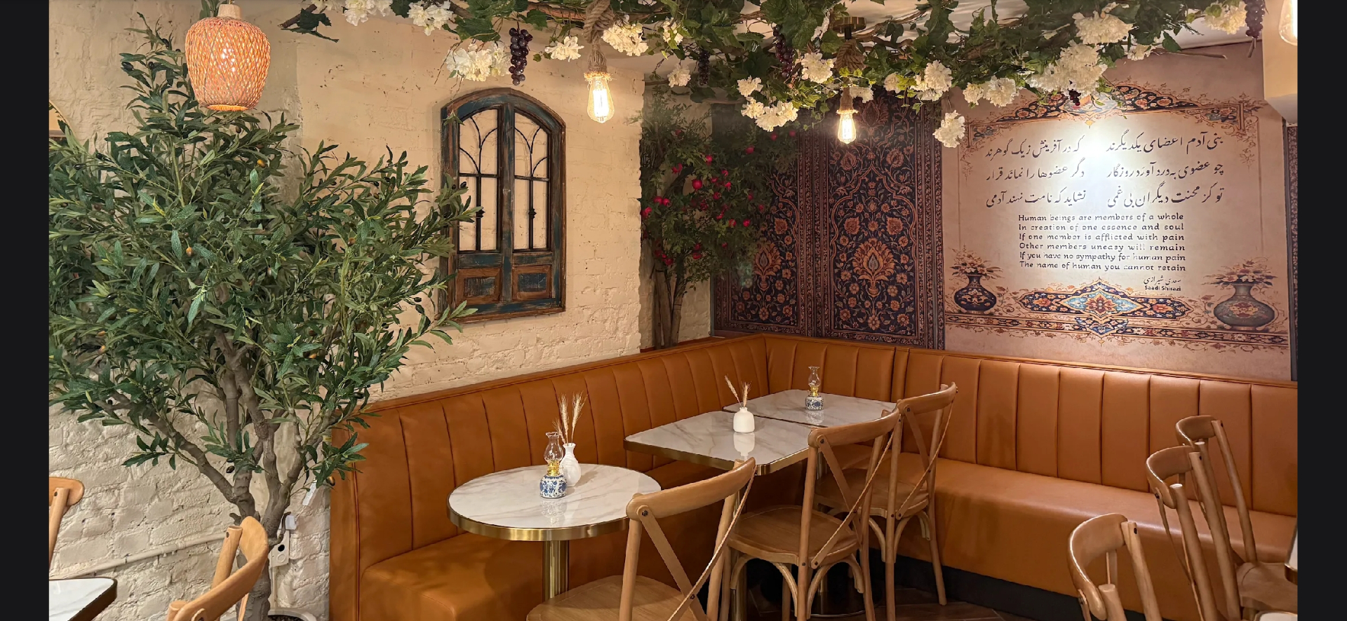 Persian poetry mural, olive tree, and arched window at Taftoon NYC